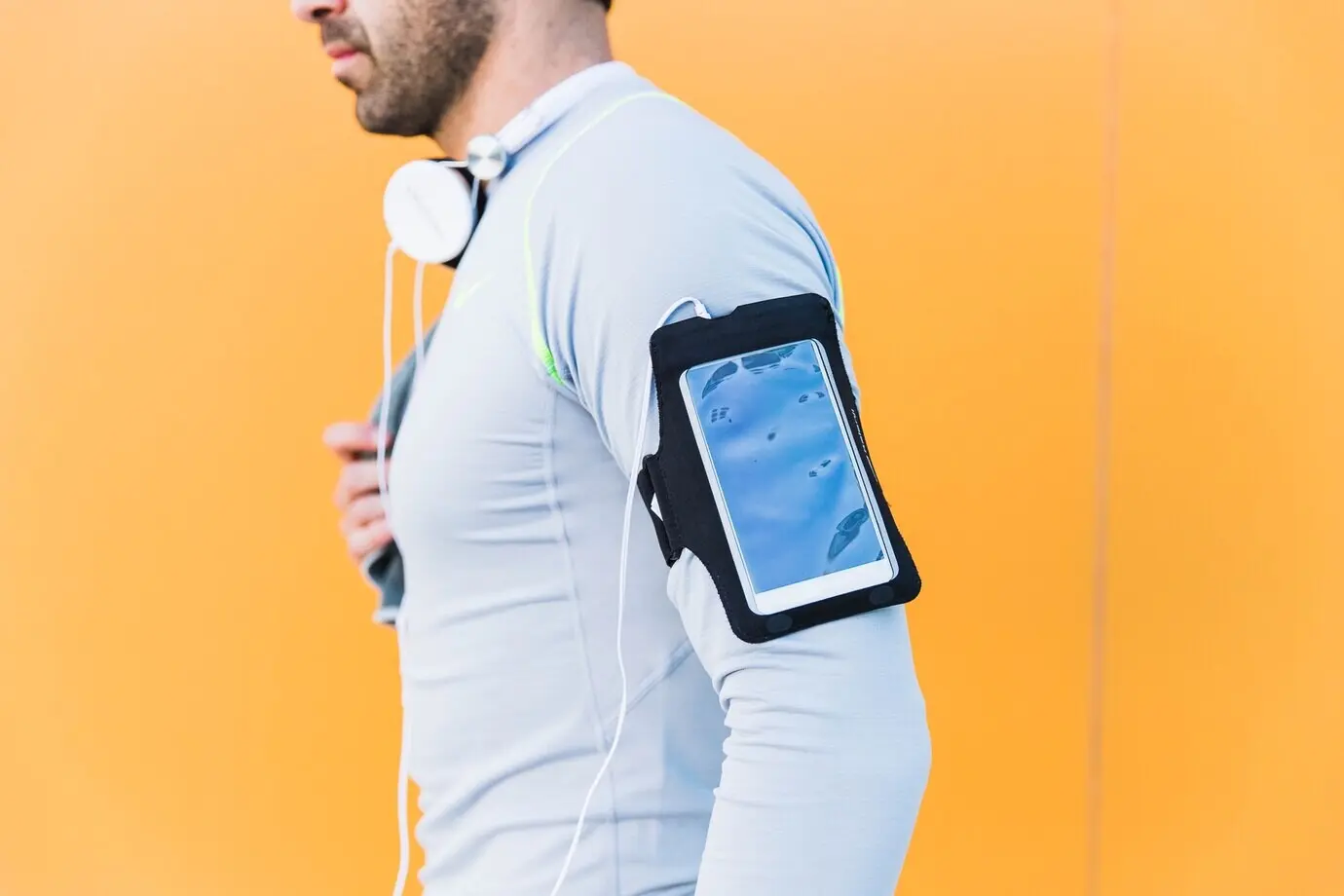 Обрезанный кадр спортсмена со смартфоном на нарукавном держателе.