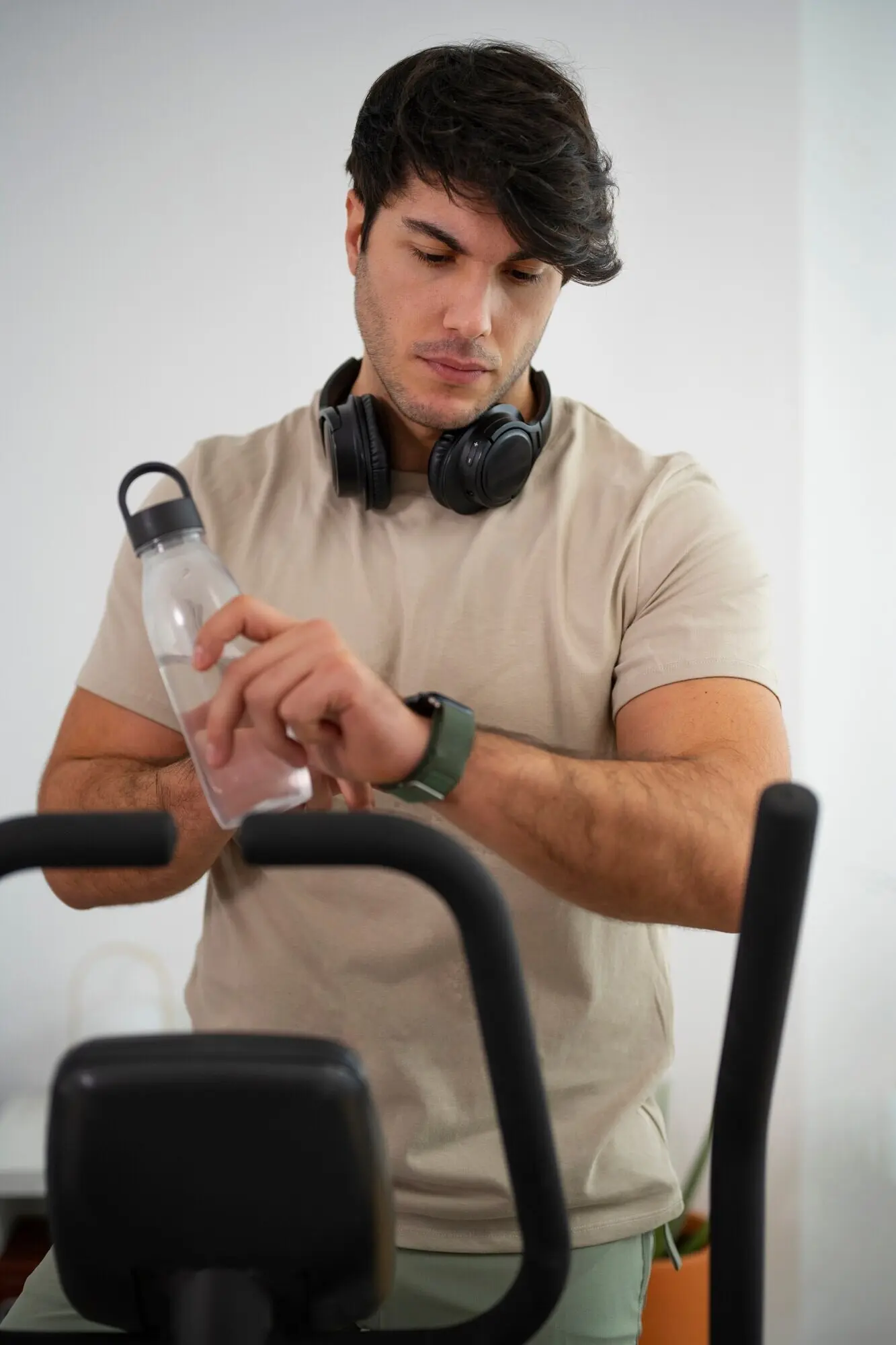 Средний план: мужчина на велотренажёре дома.